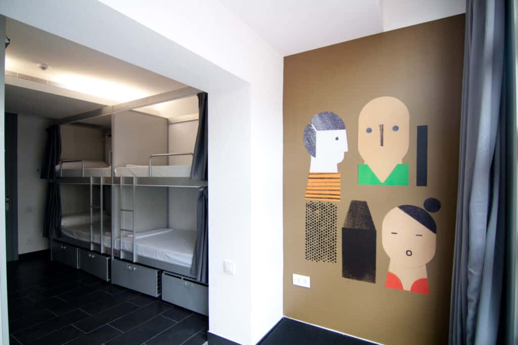 Hostel dorm room with bunk beds and vibrant wall art at St Christopher’s Berlin - Mitte.