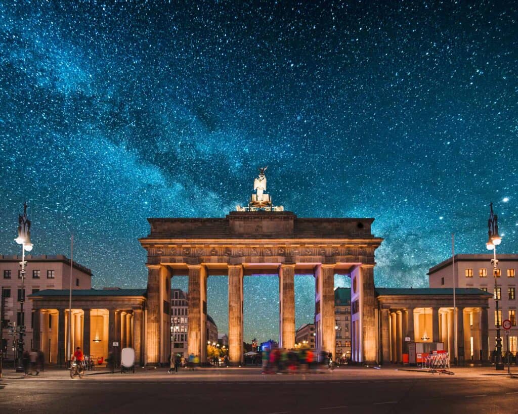 Berlin Brandenburg Gate at night with starry sky, illuminated and iconic landmark.