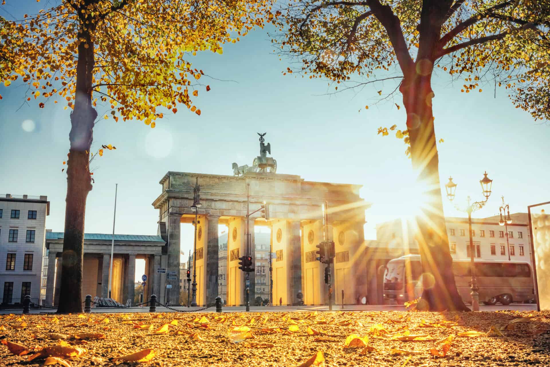 Brandenburg Gate, Berlin, with sunlight shining through trees in the morning.