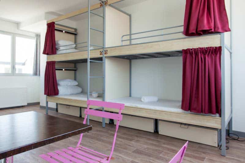 Bunk beds with red curtains in a modern hostel dorm room at St Christopher’s Berlin - Mitte.