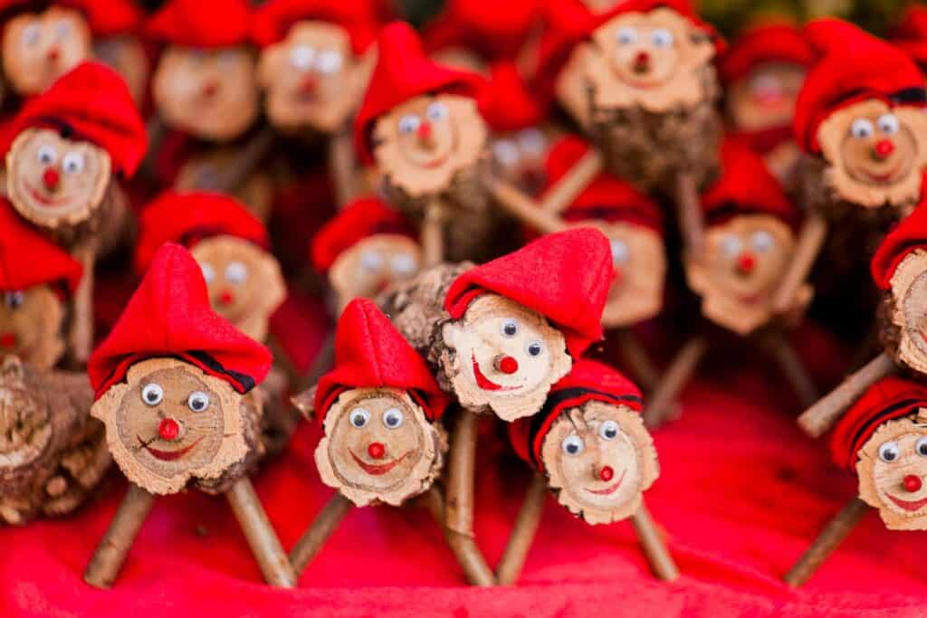 Festive Christmas wooden figurines with Santa hats and smiling faces for holiday decor.