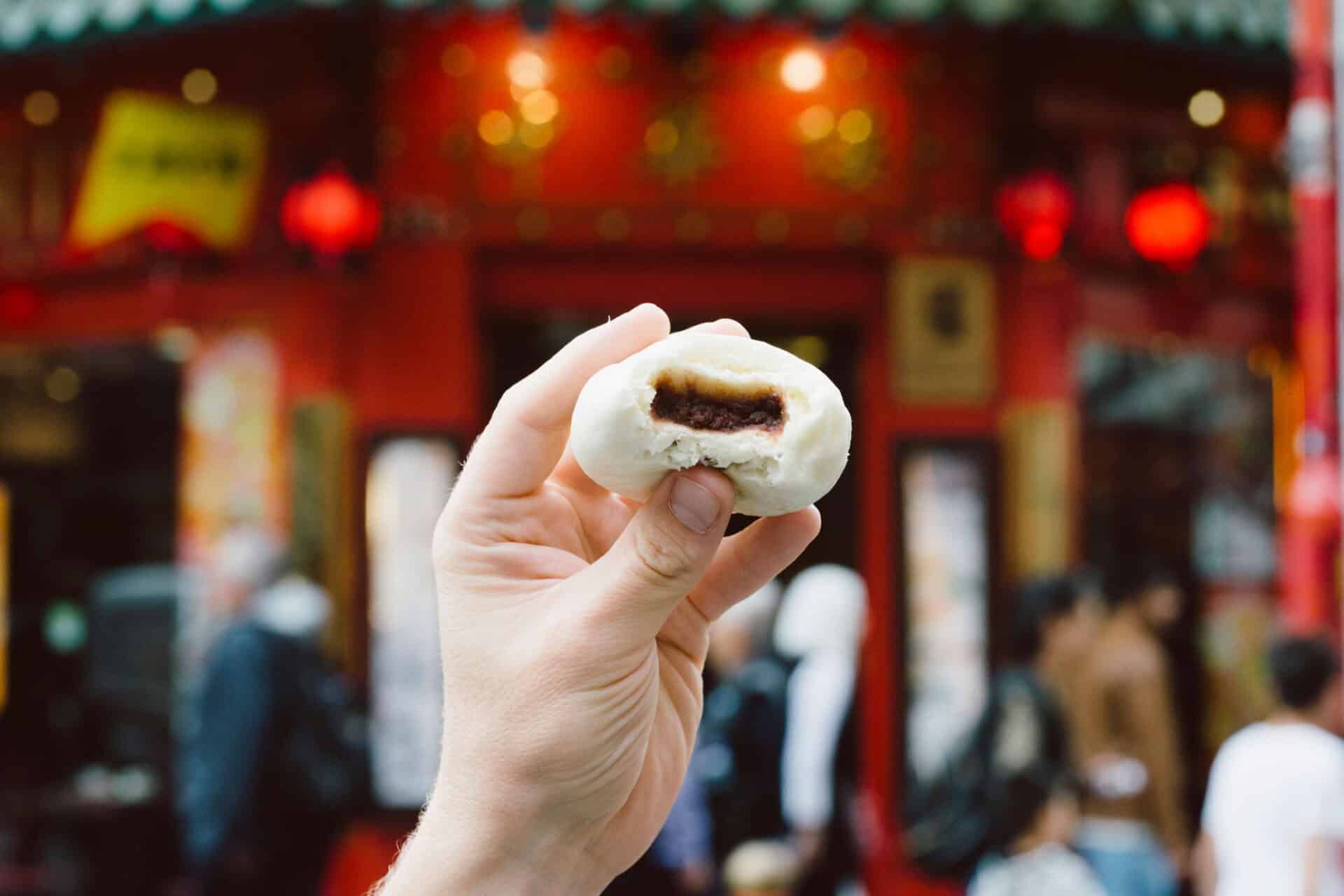 Hand holding a chocolate-filled bun in front of Mitte Hostel, Berlin.