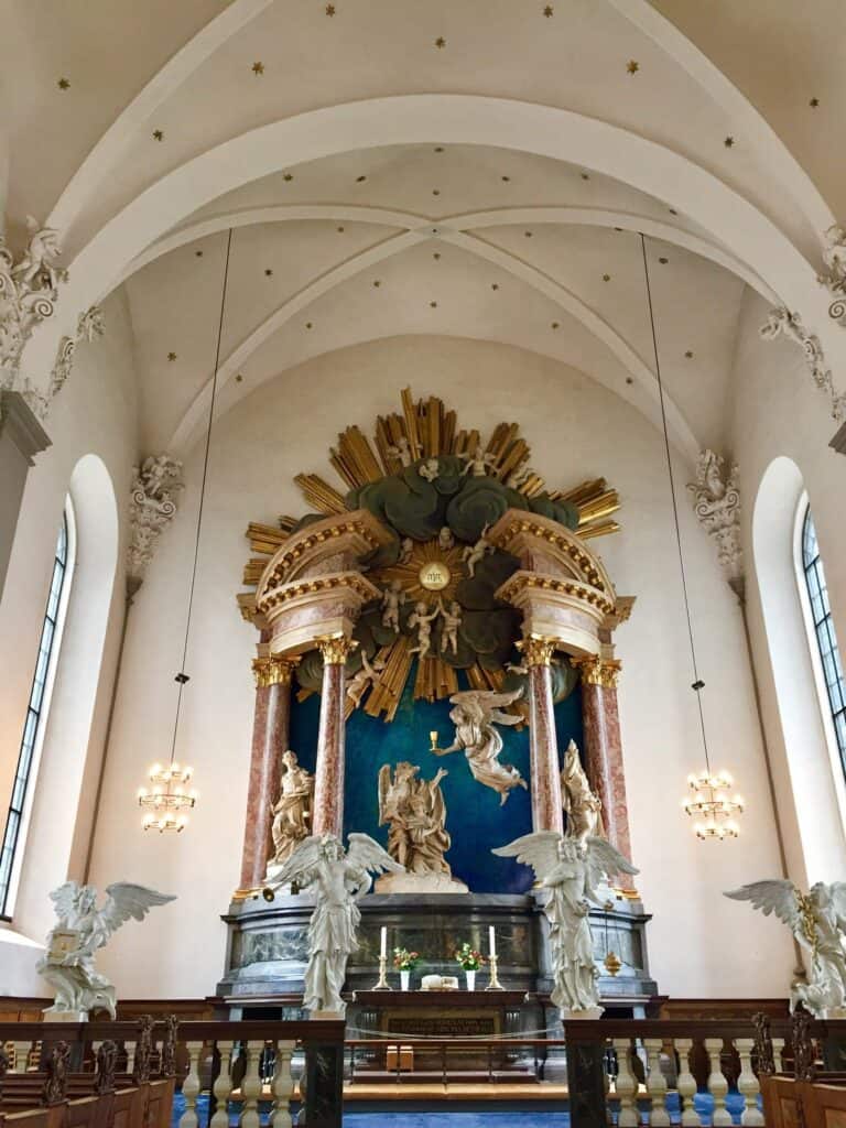 Interior view of St Christopher’s Berlin hostel with ornate altar and angel sculptures.