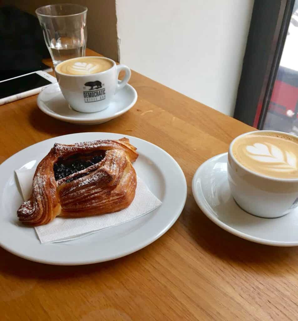 Coffee and pastry at St Christopher’s Berlin hostel in Mitte, with latte art and a chocolate croissa.