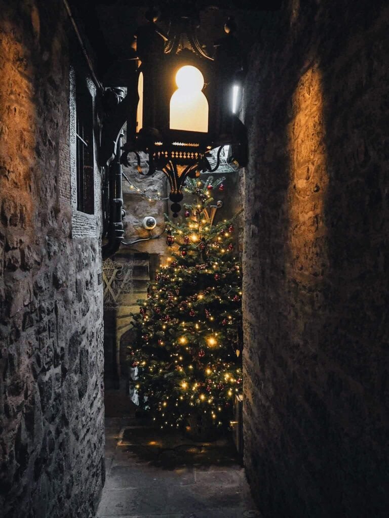 Narrow stone corridor with decorated Christmas tree and warm lighting at St Christopher’s Berlin hos.