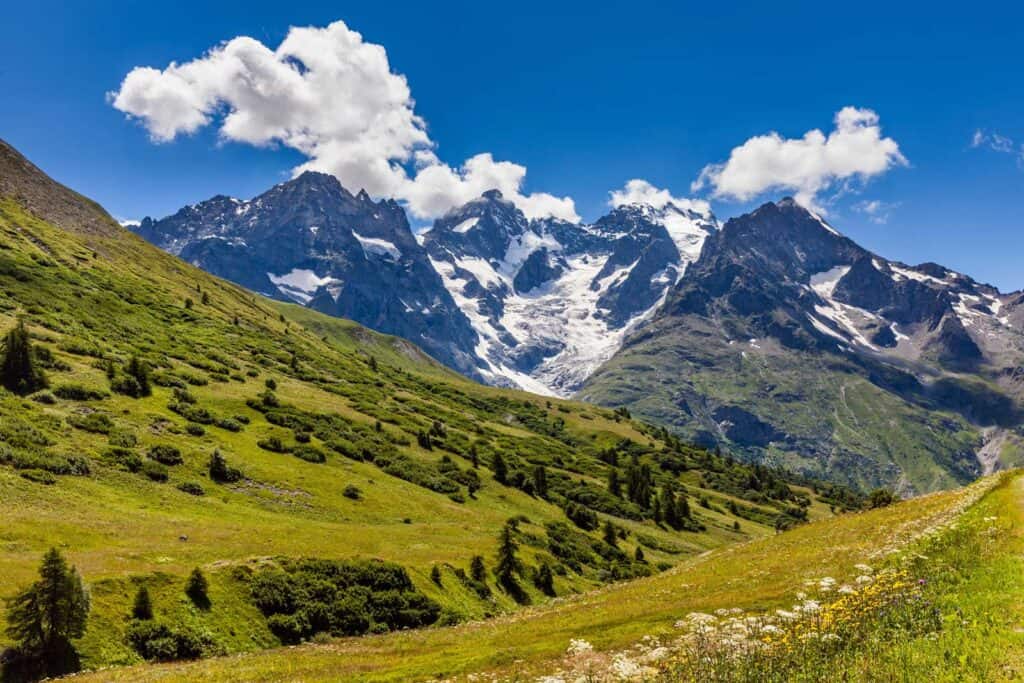 Mountain landscape with snow-capped peaks and lush green valleys in the Alps.