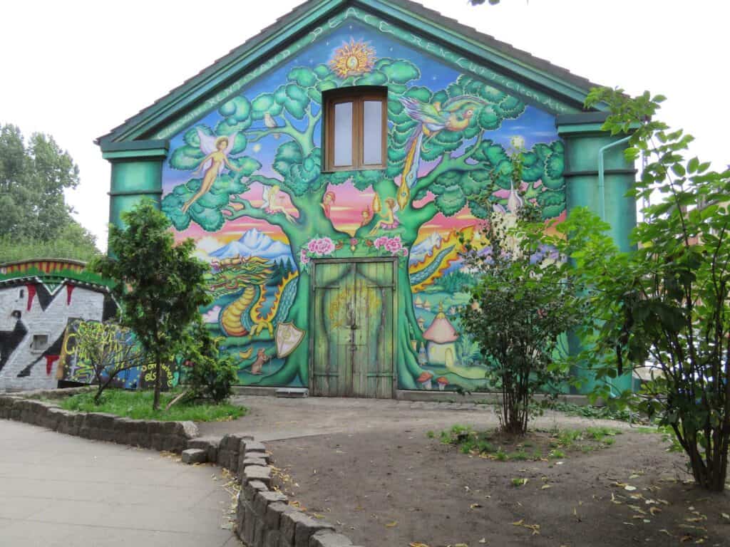 Colorful street art mural depicting a whimsical nature scene on the hostel facade.