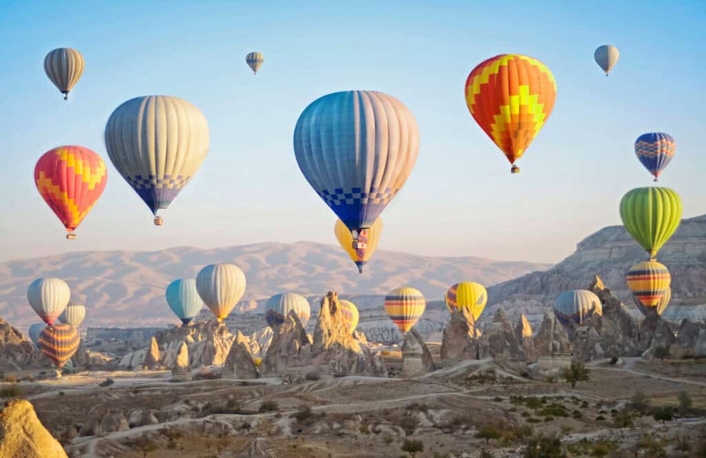 Hot air balloons flying over Cappadocia's unique rock formations at sunrise.