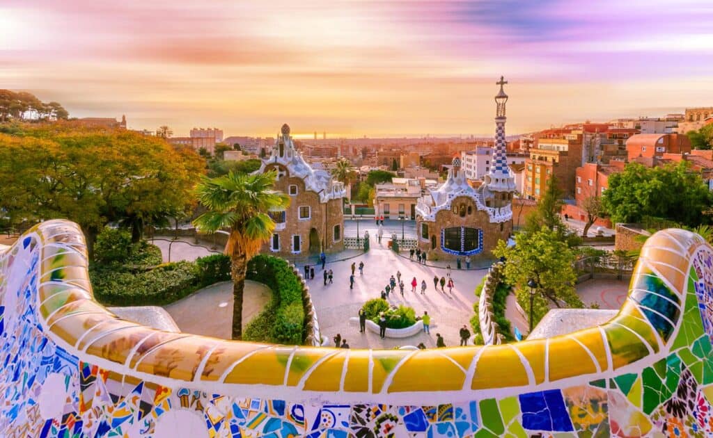 Vibrant mosaic architecture at Park Güell in Barcelona with panoramic city views at sunset.