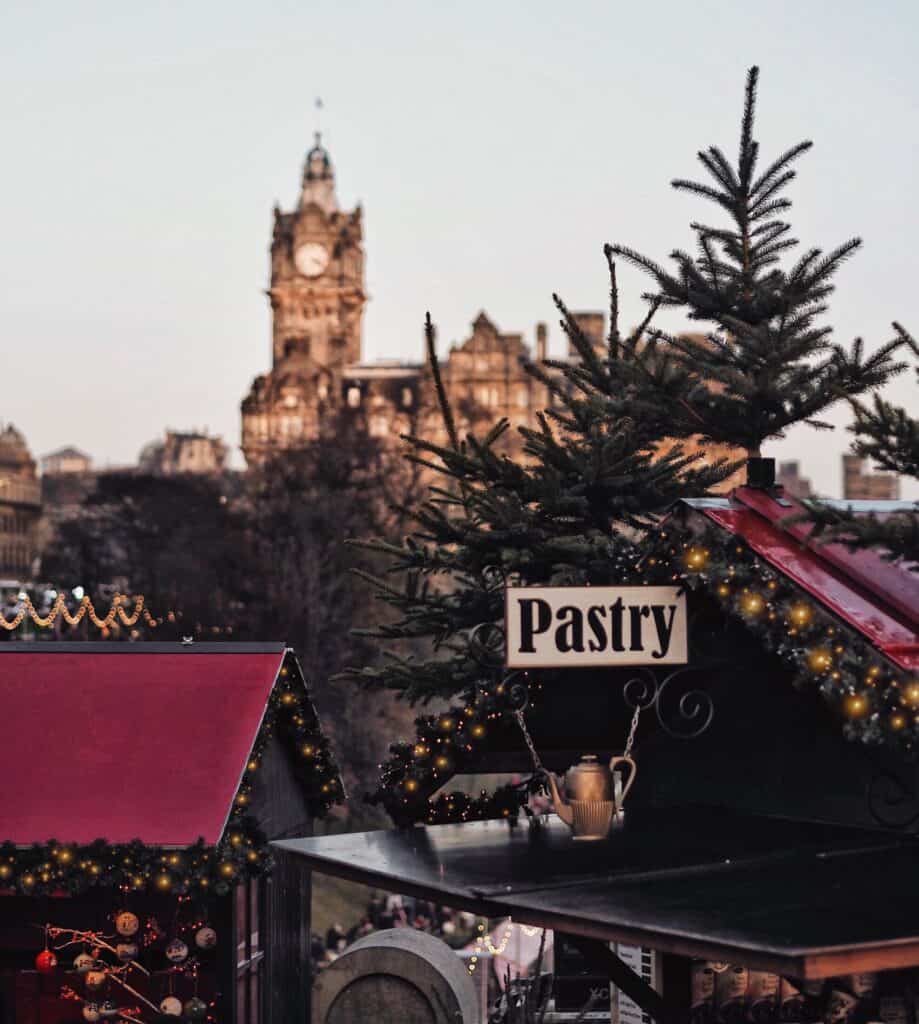 Pastry stall at Berlin Christmas market with festive decorations and cityscape background.