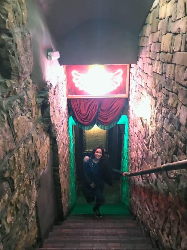 Entrance to Mitte Hostel with neon angel wings sign and stone walls, inviting guests into a vibrant.