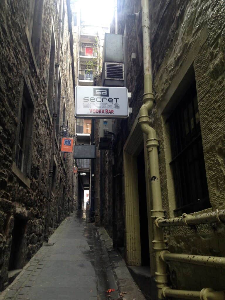 Narrow alleyway leading to Mitte Hostel with signage and pipes on walls in Berlin.