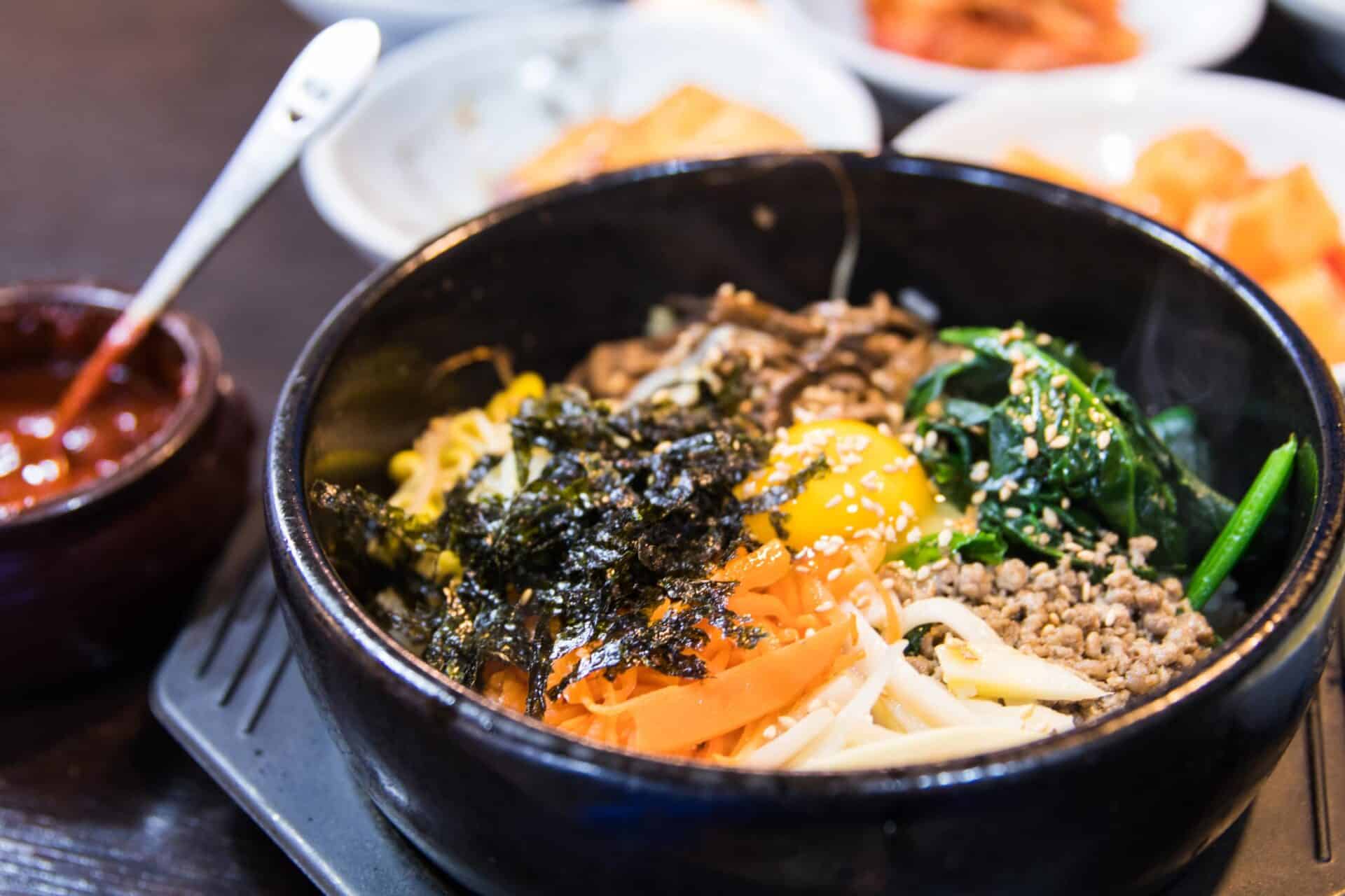 Traditional Korean Bibimbap served in a hot stone bowl with vegetables and egg.
