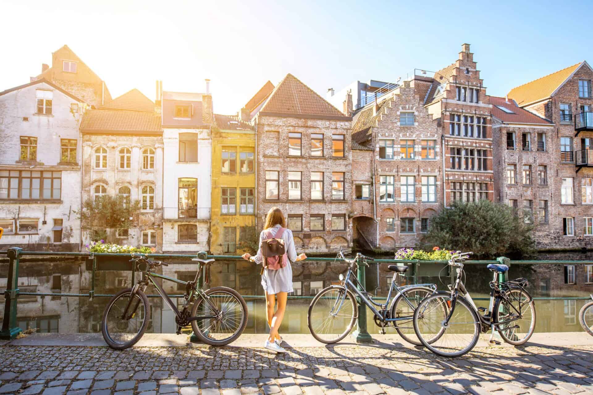 Young woman with bicycles overlooking historic Berlin buildings by the river.