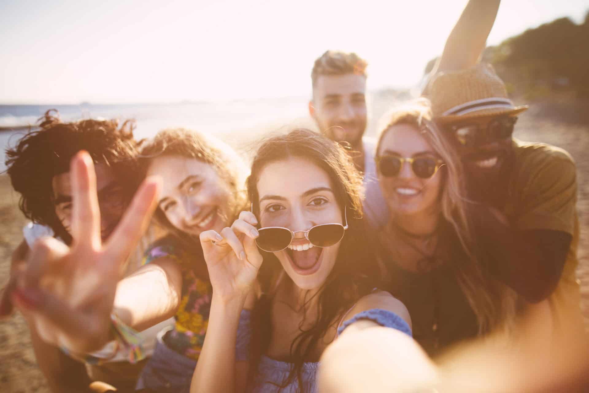 Group of young friends enjoying a sunny day at the beach in Berlin, smiling and taking a selfie.