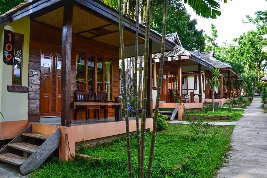 Wooden bungalows at Mitte Hostel Berlin, surrounded by lush greenery and tropical plants. Perfect fo.