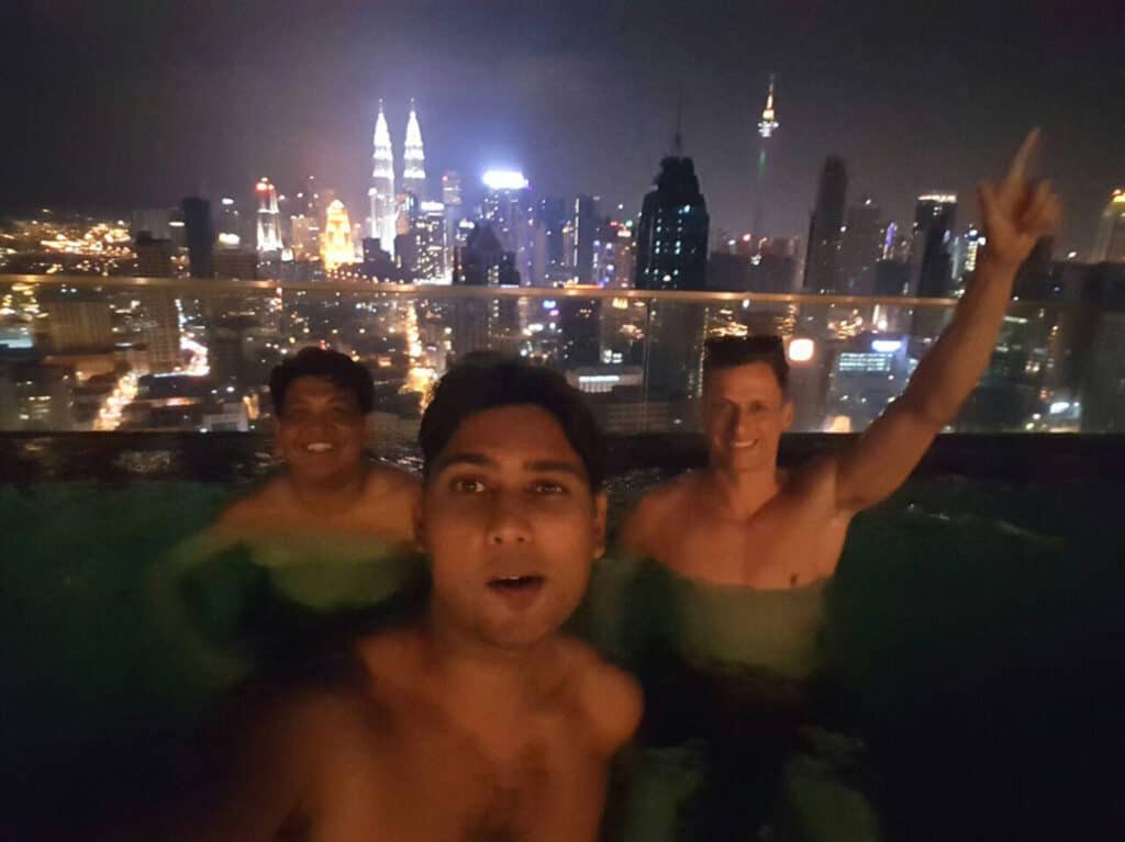 Group of friends enjoying rooftop pool with Berlin skyline at night.