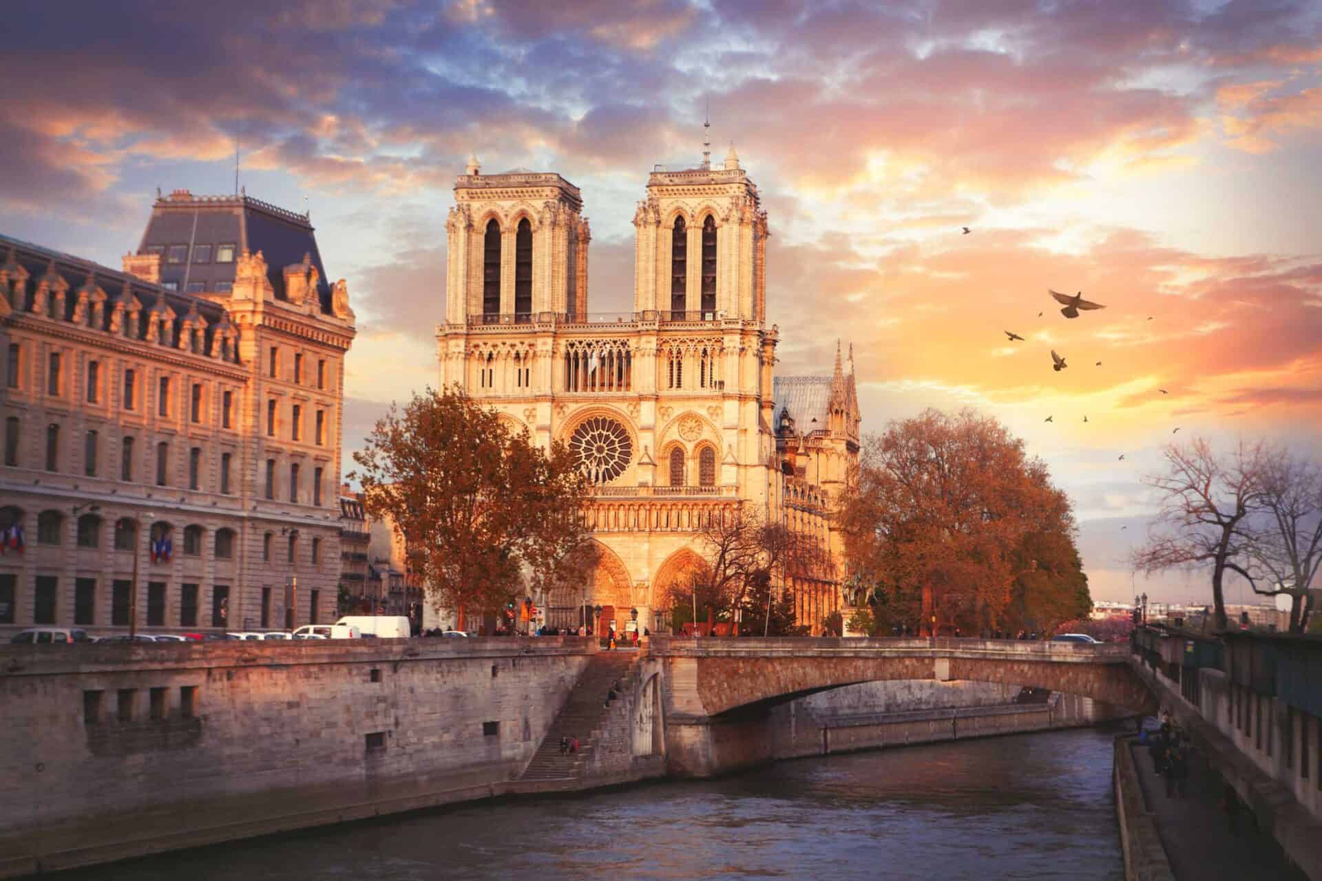 Notre-Dame Cathedral, Paris, during sunset with a colourful sky and flying birds.
