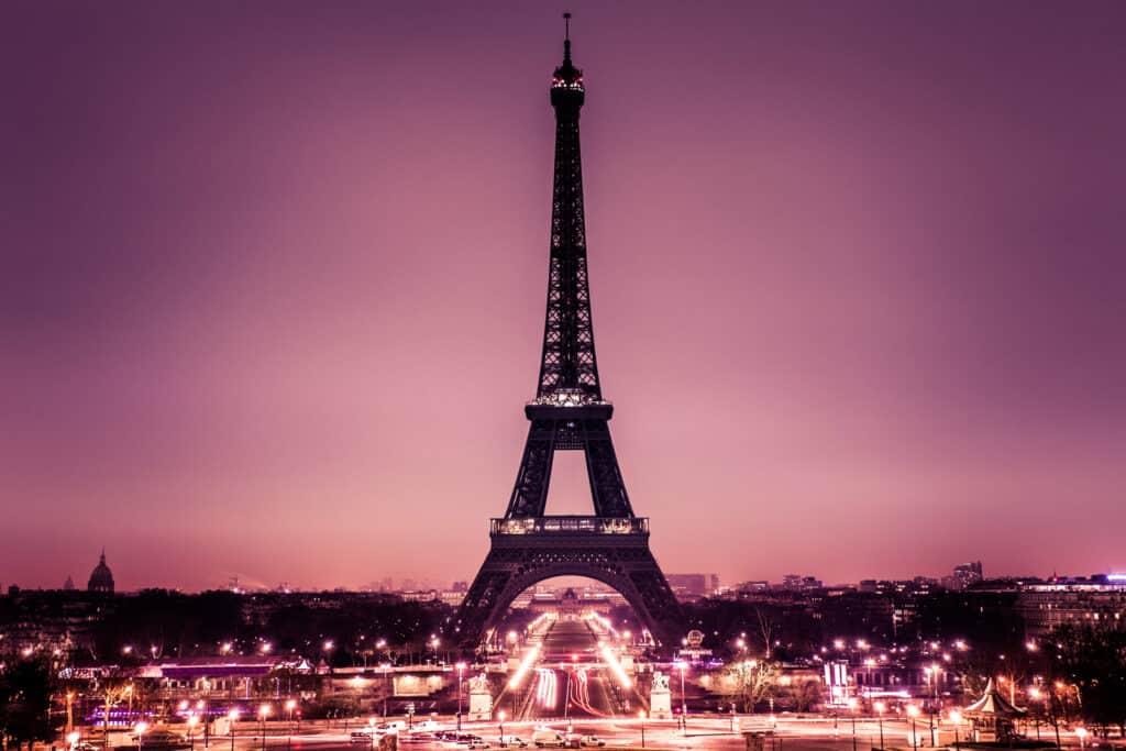 Eiffel Tower illuminated at dusk with city lights in the background.