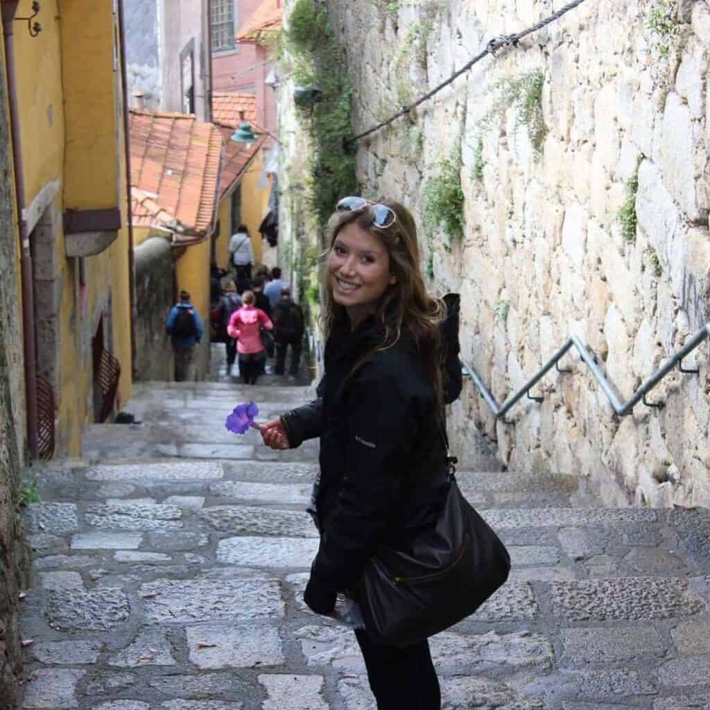 Woman smiling on cobbled street in Berlin's Mitte district with historic buildings.