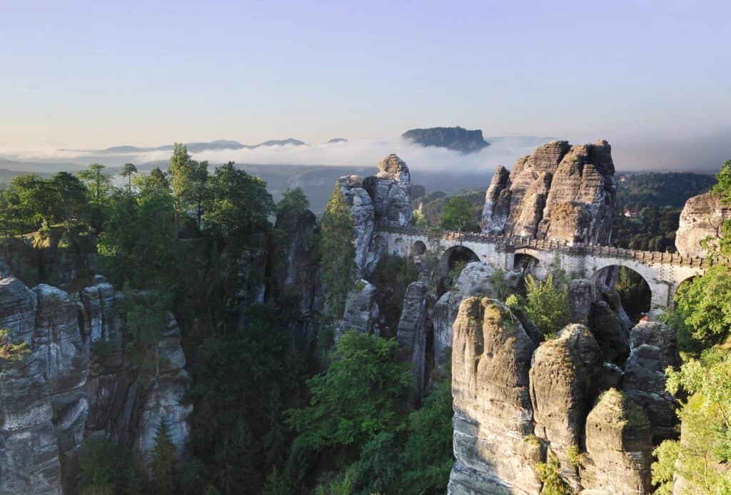 Scenic view of towering rock formations and lush greenery in a mountain landscape at dawn.