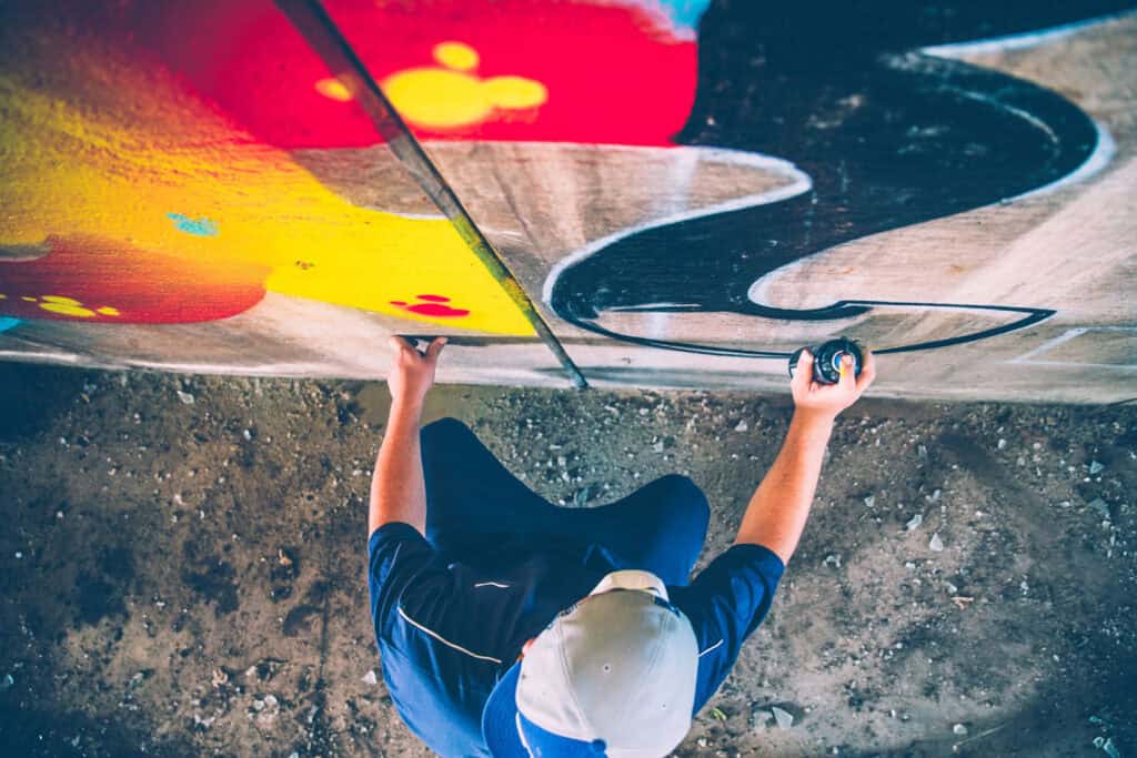 Young person climbing graffiti-covered wall at Mitte Hostel Berlin, vibrant street art backdrop.