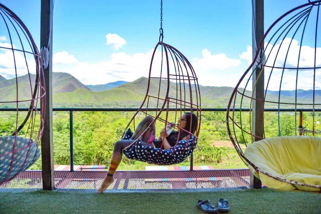 Outdoor balcony with hanging chairs overlooking scenic mountains and lush greenery in Berlin.