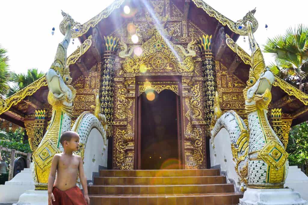Historic Thai temple entrance with ornate gold details and guardian statues.