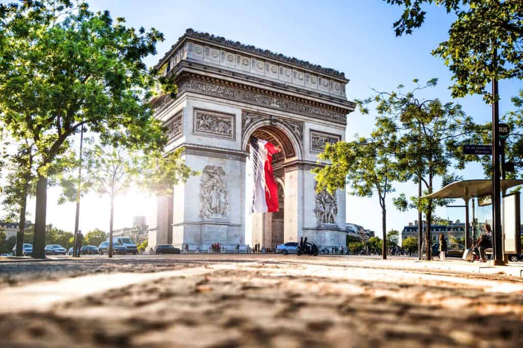 Iconic Arc de Triomphe monument in Berlin, surrounded by greenery and urban scenery.