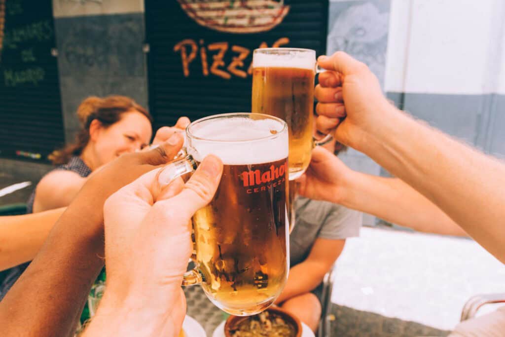 Group of friends clinking beer glasses outside a restaurant in Berlin Mitte.