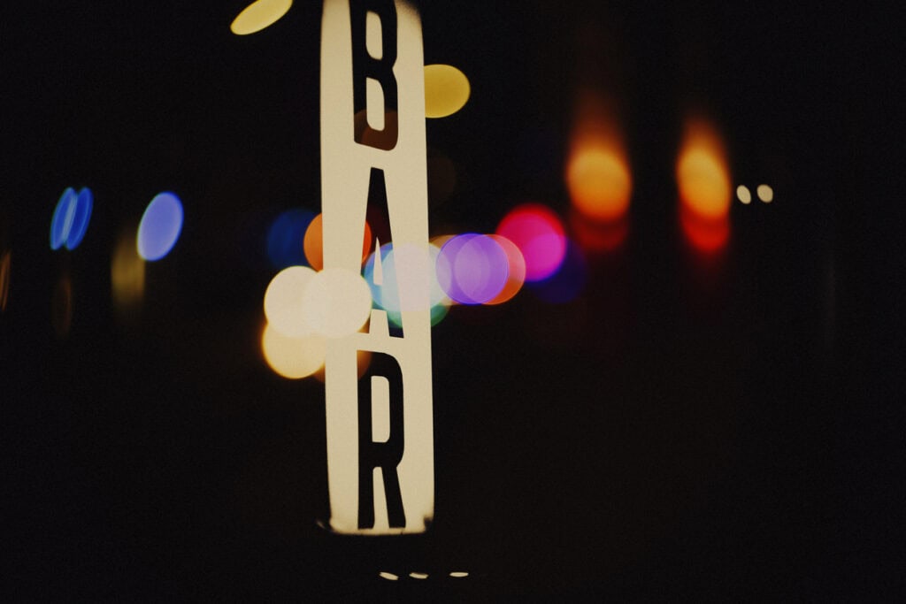 Modern hostel sign in Berlin Mitte with colourful city lights in background.