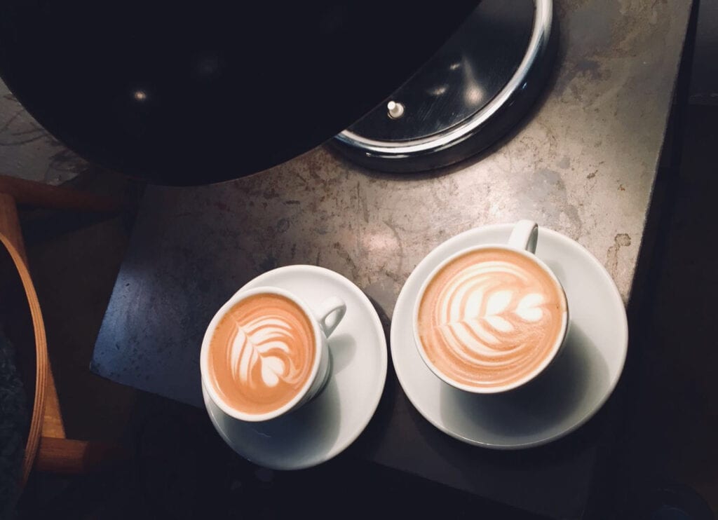Coffee cups with latte art on a dark table at St Christopher’s Berlin hostel.