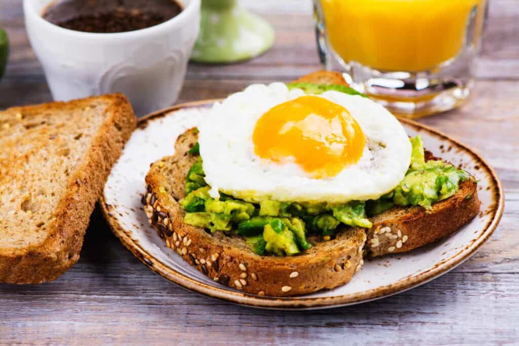 Delicious avocado toast topped with a perfectly cooked fried egg, served with coffee and juice at St.