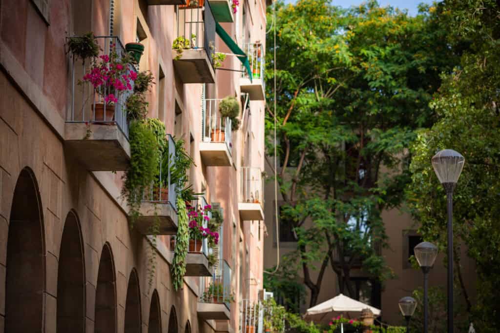 Balcony view of Mitte Hostel in Berlin with colourful flower boxes and lush green trees.