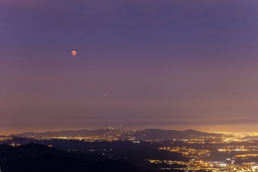 Moon over Berlin skyline at dusk, showcasing the city’s vibrant lights and scenic views.