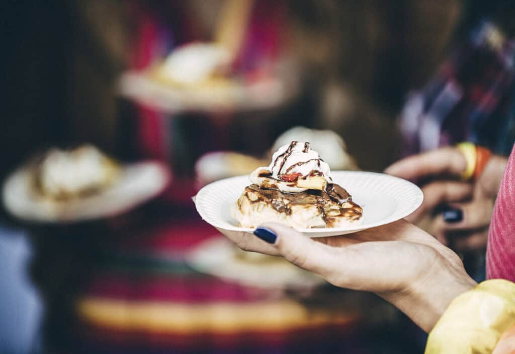 A person holding a plate of desserts at a social hostel event.