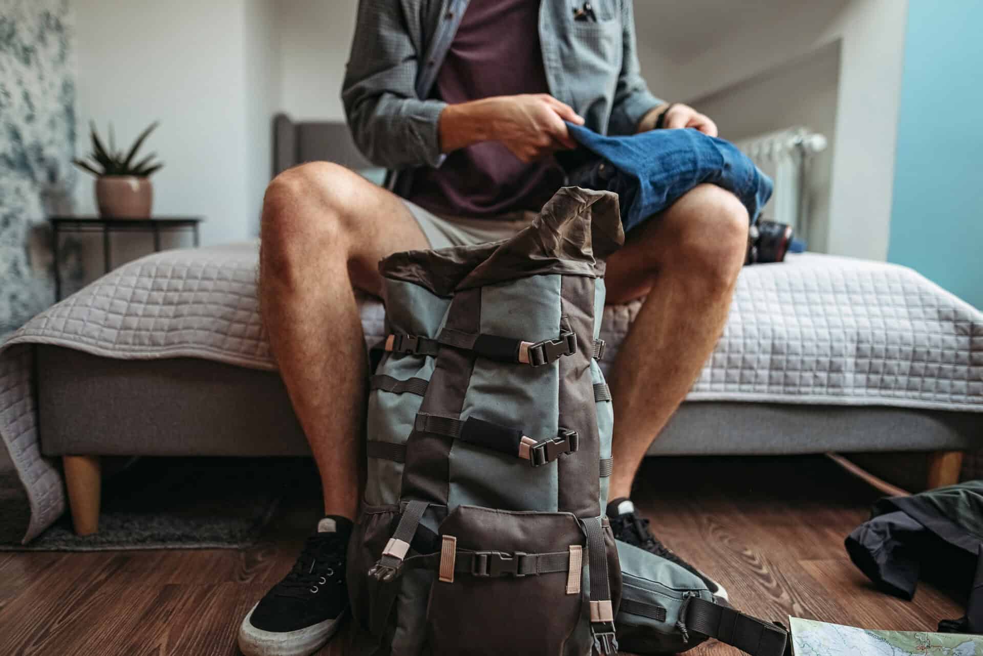Young man packing a backpack in a modern hostel room in Berlin, Mitte district.
