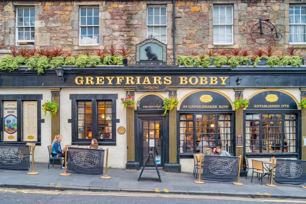 A busy social hostel bar with outdoor seating and a traditional pub facade.