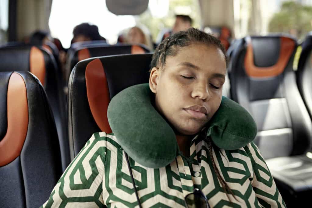 Comfortable young woman sleeping on bus with travel neck pillow.