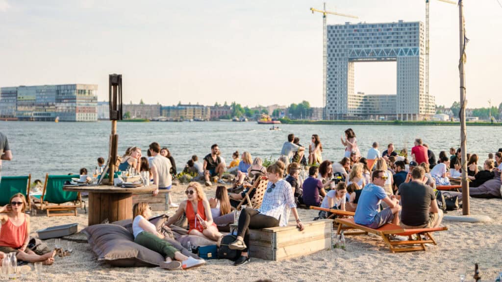 People relaxing by the river at Mitte Hostel Berlin, enjoying sunny weather and scenic views of the.