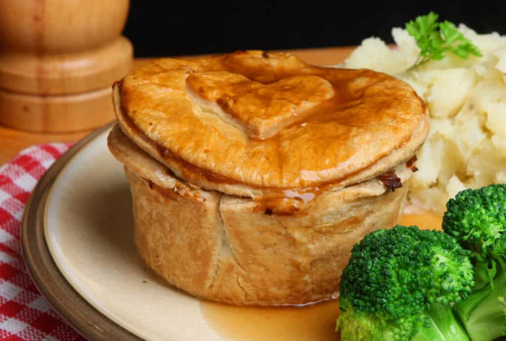 Classic British meat pie served with mashed potatoes and broccoli, traditional comfort food in Berli.