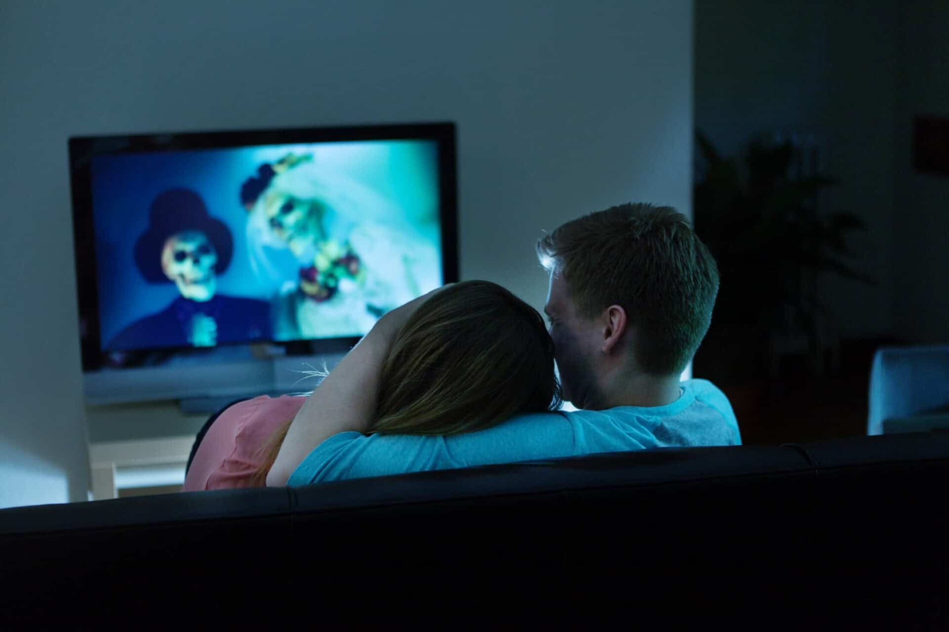 Young couple watching TV in a modern hostel lounge at St Christopher’s Berlin Mitte.