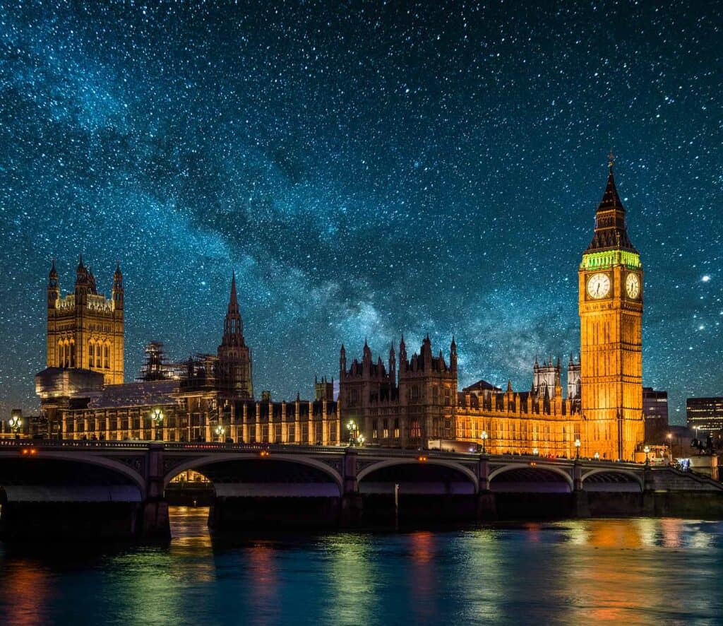 Night view of London skyline with Big Ben and the Houses of Parliament under a starry sky.