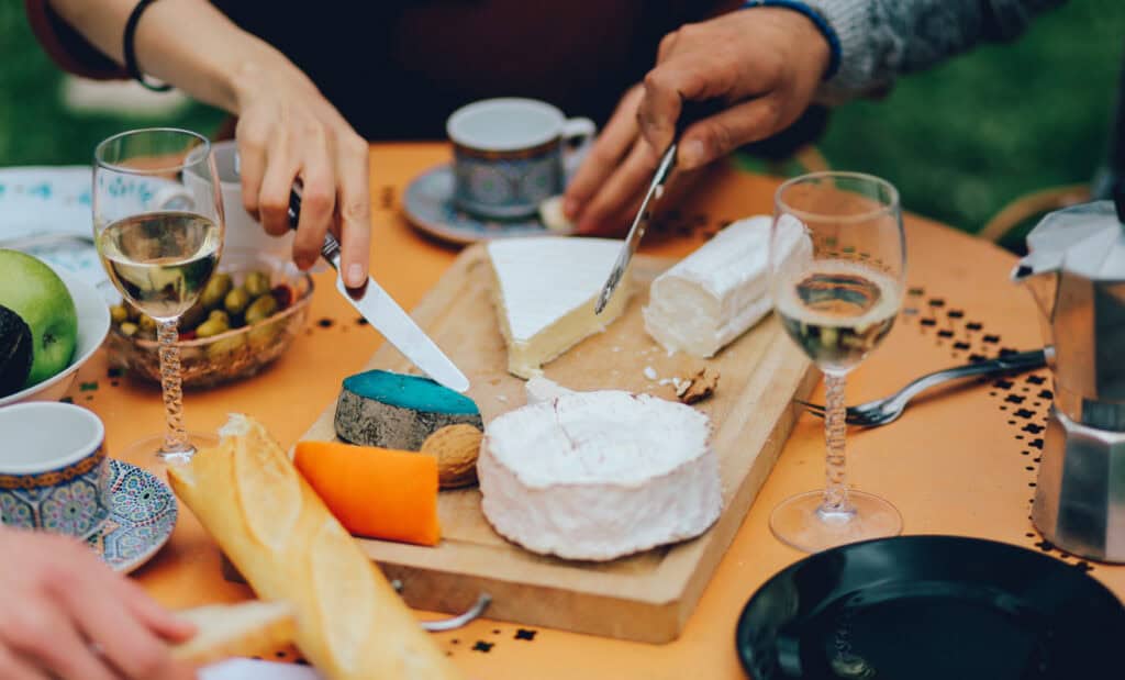 People enjoying cheese tasting at Mitte Hostel, Berlin, with wine glasses and cheese platter.