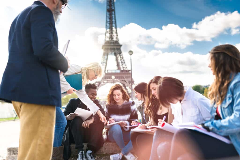 Group of young tourists reading maps and guides near the Eiffel Tower replica in Berlin, showcasing.