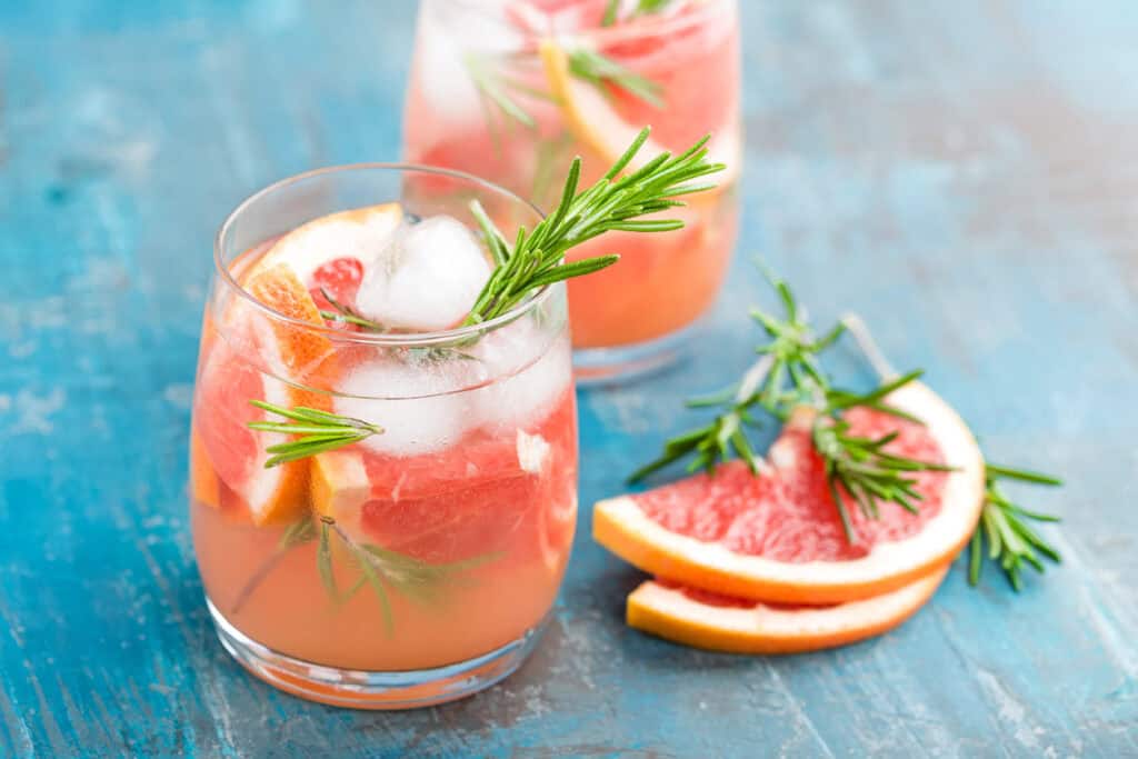 Refreshing grapefruit cocktail with rosemary garnish in a glass.