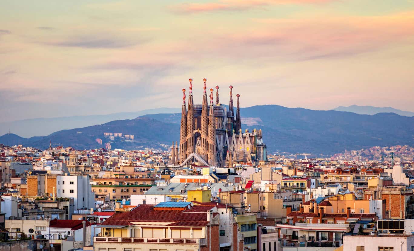 Iconic Sagrada Família basilica in Barcelona with cityscape at sunset.