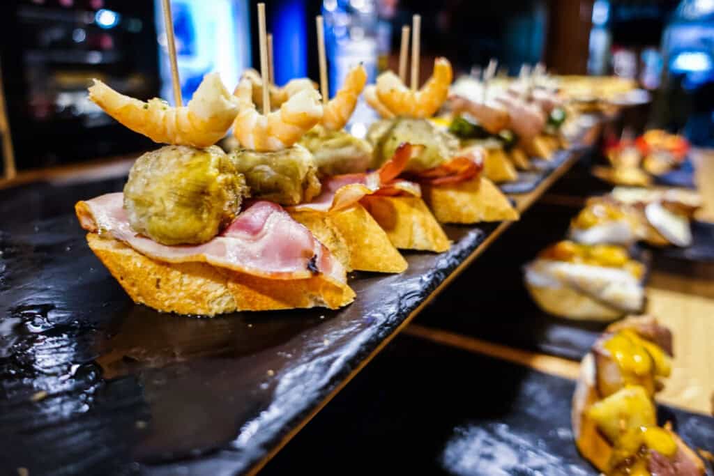 Seafood tapas with shrimp, fish, and vegetables served on a black slate platter.