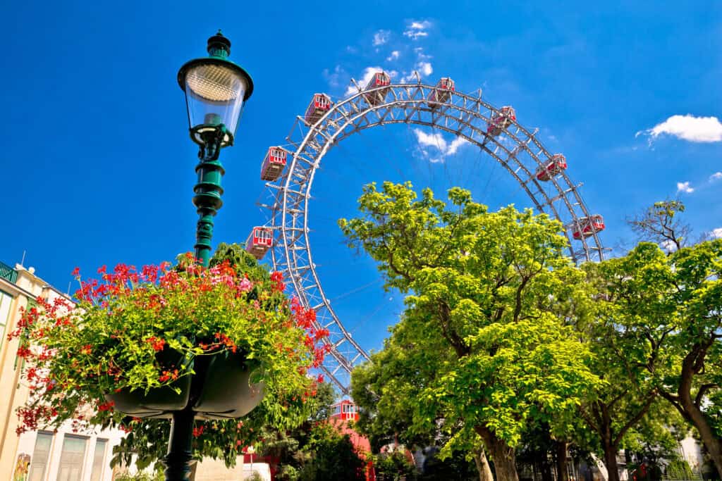 Iconic Ferris wheel in Berlin's Mitte district with lush trees and a vintage street lamp, showcasing.