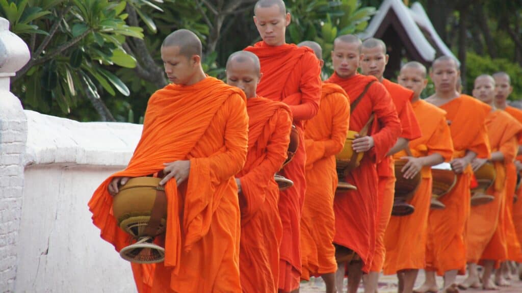 Young monks in orange robes walking in a line at Mitte Hostel, Berlin.